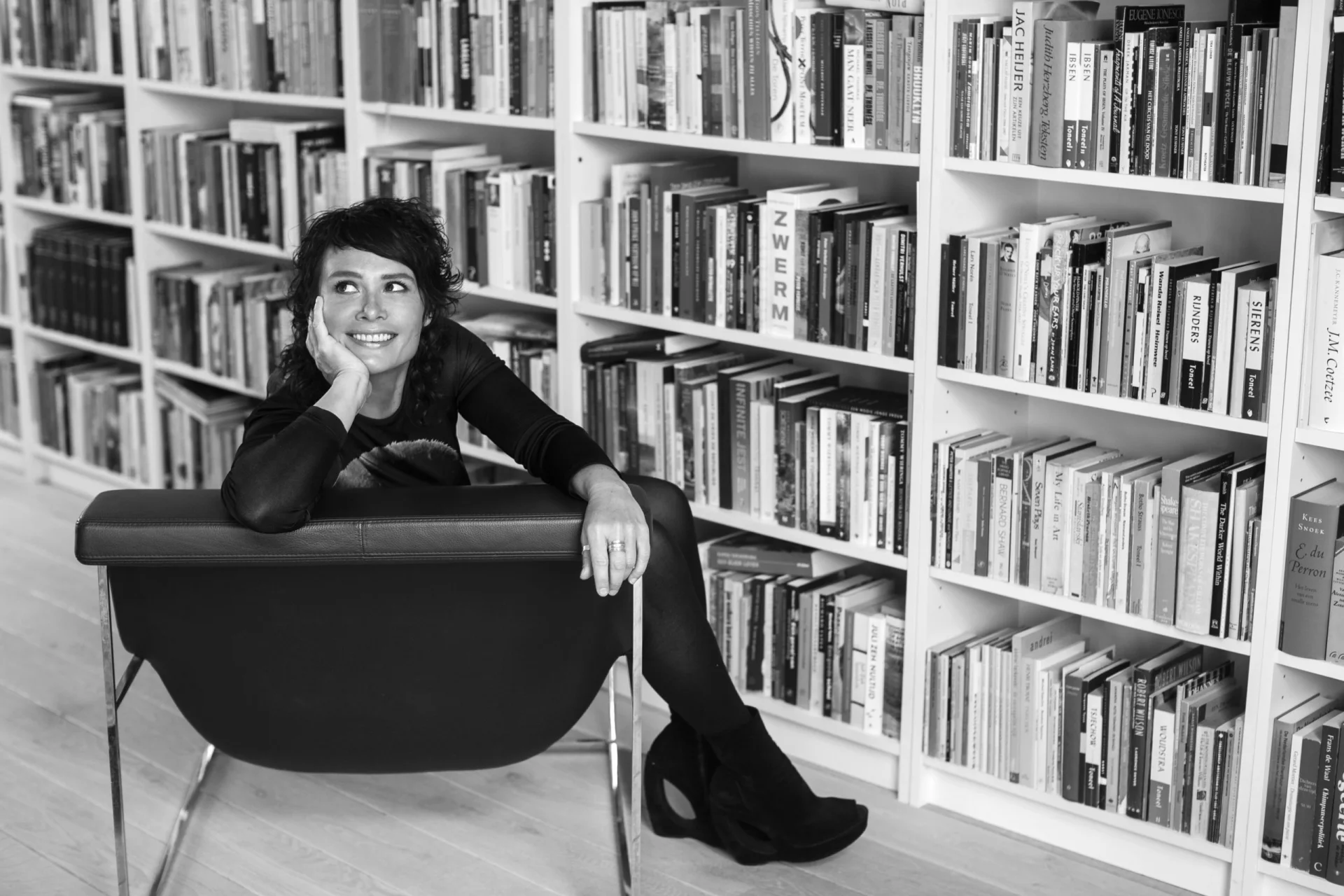 Griet Op de Beeck voor een wand vol boeken